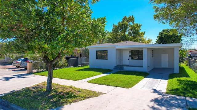 view of front of property with stucco siding, a front lawn, fence, concrete driveway, and an attached carport