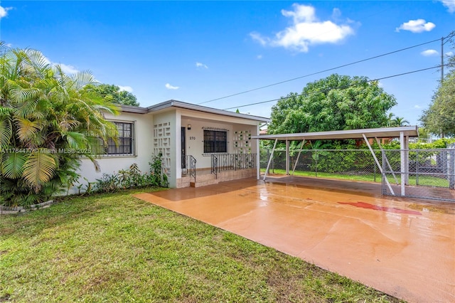 view of patio with concrete driveway, fence, and a carport