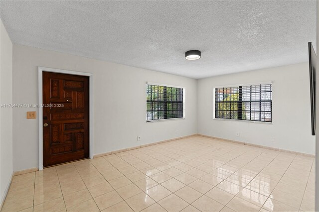 unfurnished room featuring a wealth of natural light, light tile patterned floors, and baseboards