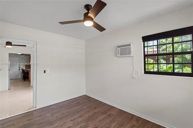 spare room featuring visible vents, wood finished floors, a ceiling fan, and a wall mounted AC