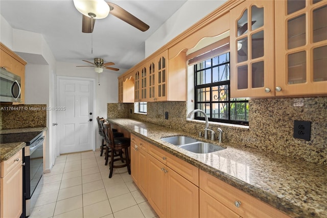 kitchen featuring stainless steel microwave, electric range oven, decorative backsplash, a ceiling fan, and a sink