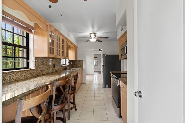 kitchen featuring tasteful backsplash, light tile patterned floors, stainless steel appliances, a ceiling fan, and a sink