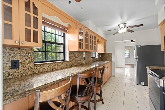 kitchen with glass insert cabinets, ceiling fan, light tile patterned floors, stainless steel appliances, and a sink