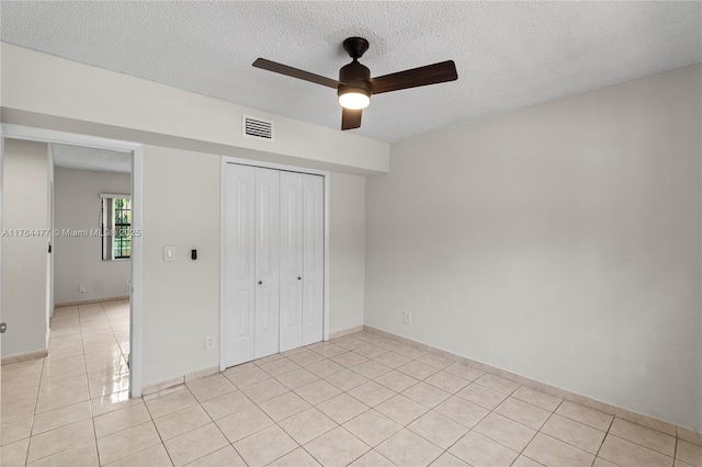 unfurnished bedroom featuring visible vents, ceiling fan, light tile patterned floors, a closet, and a textured ceiling