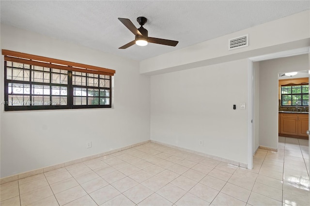 spare room with light tile patterned floors, visible vents, a sink, ceiling fan, and a textured ceiling