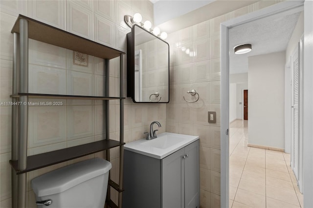 bathroom featuring tile patterned floors, toilet, tile walls, and vanity