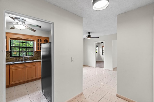 kitchen featuring light tile patterned floors, a ceiling fan, freestanding refrigerator, and a sink