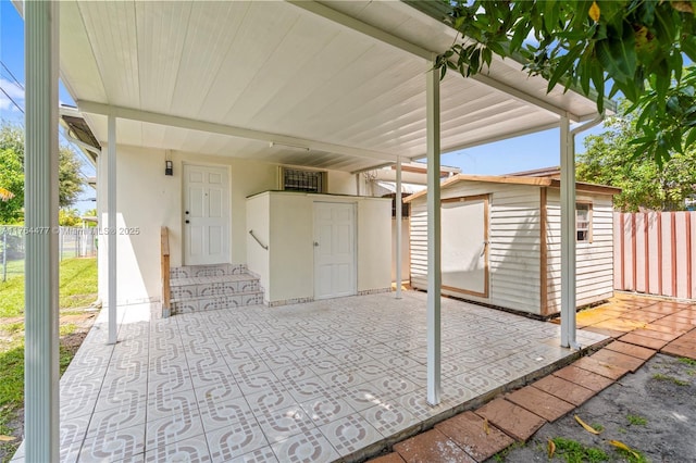 view of patio / terrace featuring a storage shed, fence, and an outbuilding