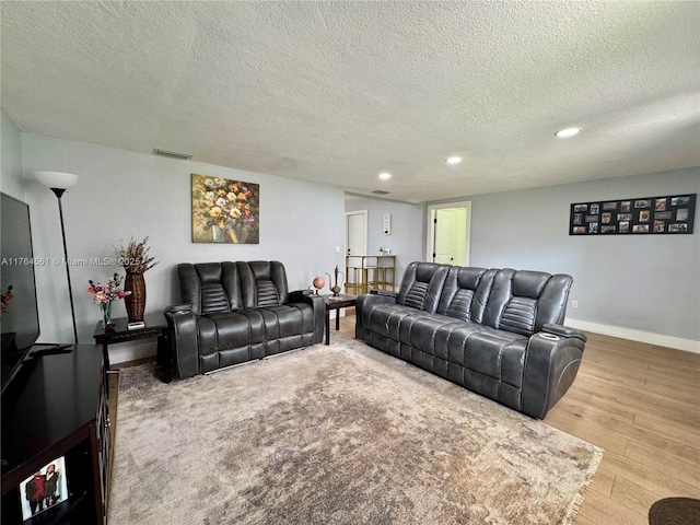 living room with visible vents, a textured ceiling, wood finished floors, recessed lighting, and baseboards