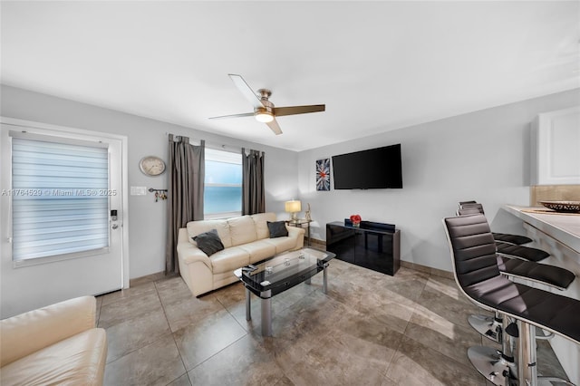 living area featuring baseboards and ceiling fan