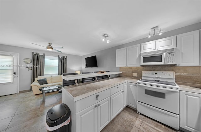 kitchen featuring tasteful backsplash, open floor plan, white cabinetry, white appliances, and a peninsula