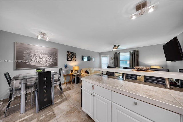 kitchen featuring white cabinetry, a ceiling fan, and open floor plan