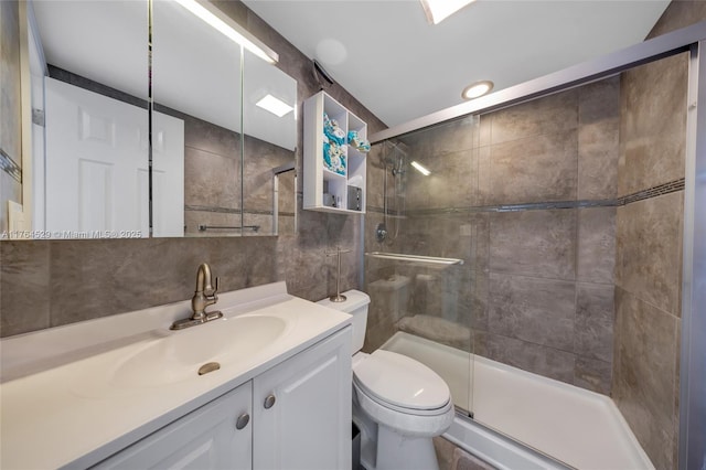 full bathroom with toilet, backsplash, tile walls, a shower stall, and vanity