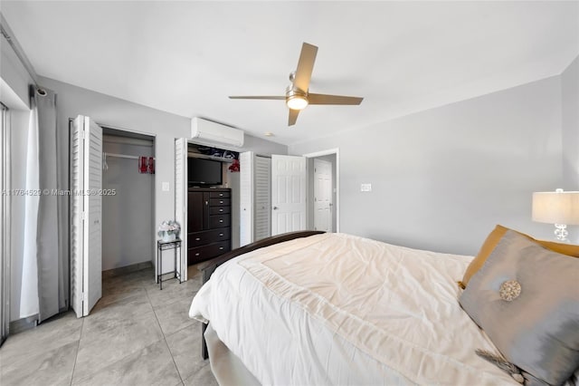 bedroom featuring light tile patterned floors, an AC wall unit, multiple closets, and a ceiling fan