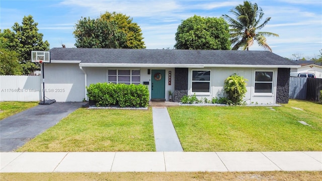 single story home with a shingled roof, a front yard, fence, and stucco siding