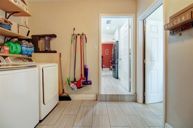 laundry room with laundry area, separate washer and dryer, visible vents, and baseboards