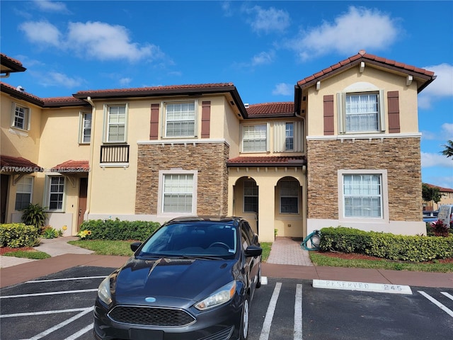 view of front of home featuring stone siding, stucco siding, and uncovered parking