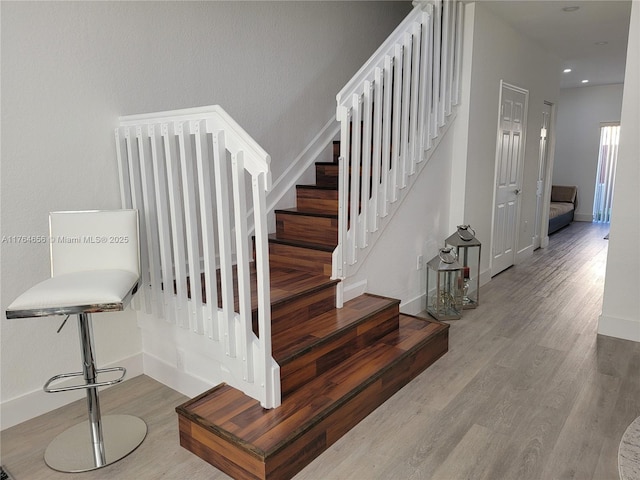 stairway featuring recessed lighting, wood finished floors, and baseboards