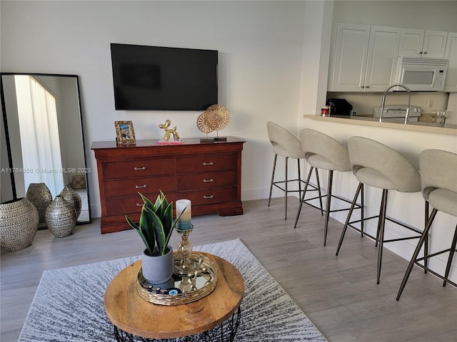 living area with baseboards and light wood finished floors