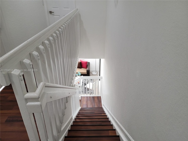 stairs featuring wood finished floors and a textured wall