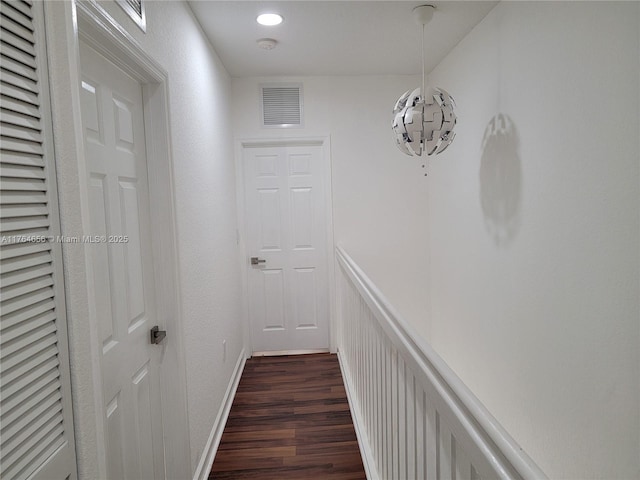 hall with dark wood-type flooring, baseboards, and visible vents