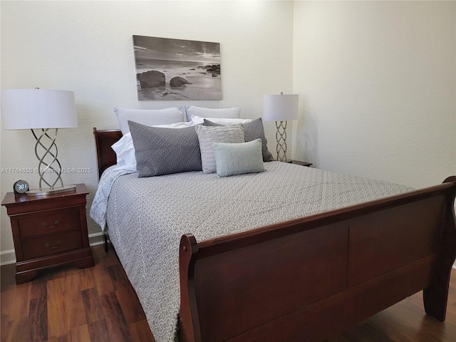 bedroom with dark wood finished floors and baseboards