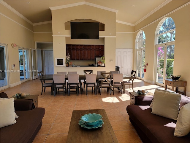 living area with a high ceiling, light tile patterned floors, baseboards, and ornamental molding