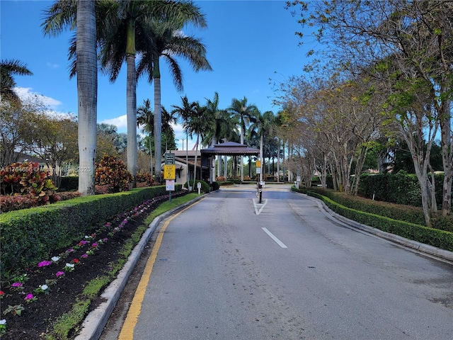 view of road with traffic signs, curbs, and a gated entry