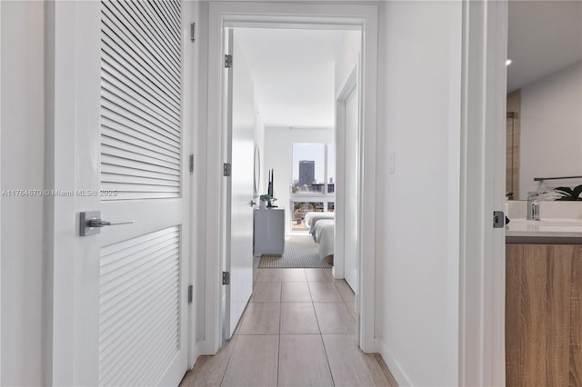 hall with light tile patterned floors and a sink