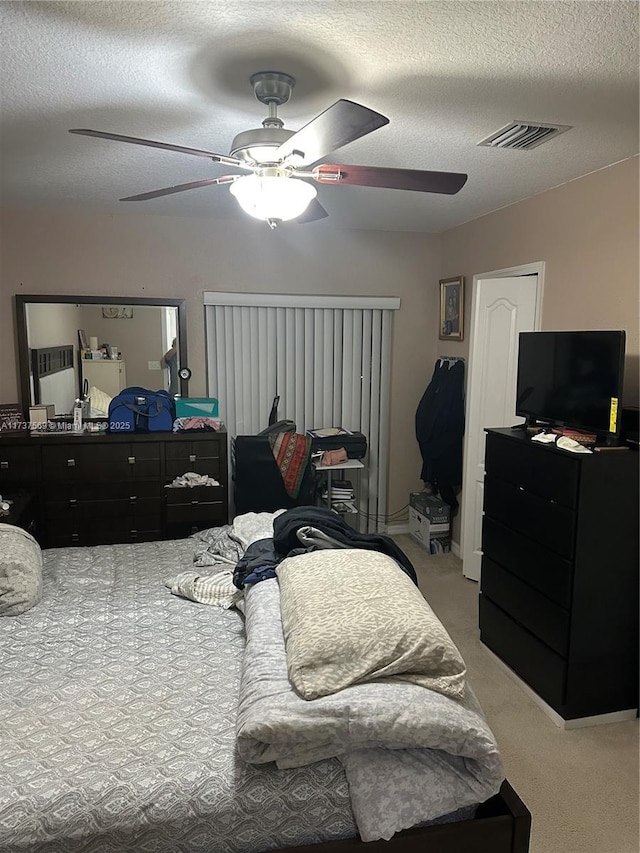 bedroom with visible vents, a textured ceiling, a ceiling fan, and carpet