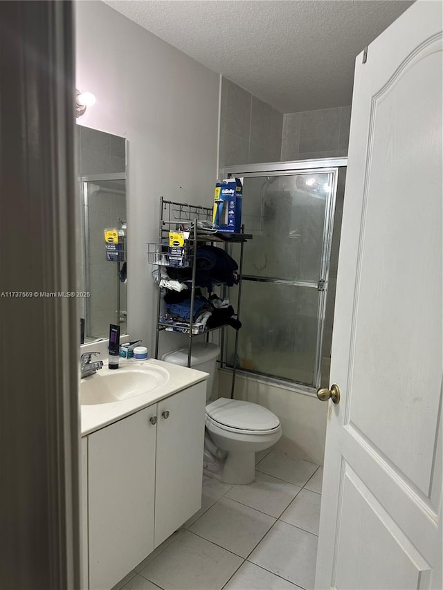 full bathroom with tile patterned floors, toilet, a textured ceiling, shower / bath combination with glass door, and vanity