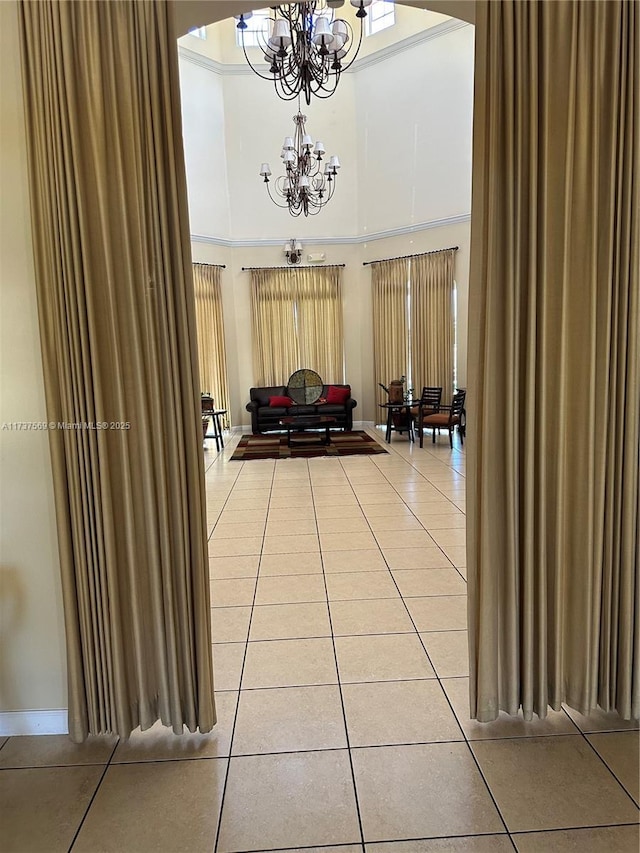 interior space featuring light tile patterned floors, a notable chandelier, and a towering ceiling