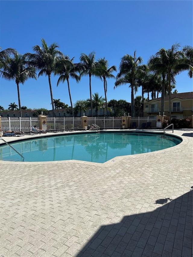 community pool with a patio and fence