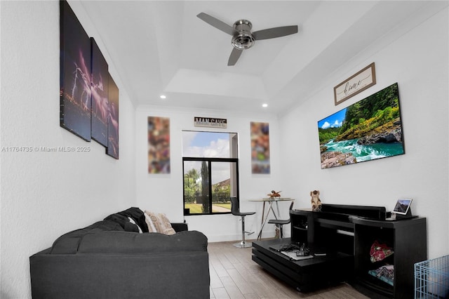 living room with wood finished floors, a ceiling fan, baseboards, recessed lighting, and a raised ceiling