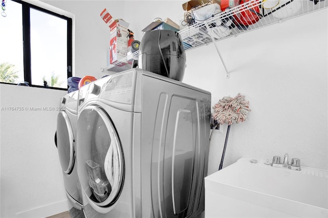 washroom with laundry area, washing machine and dryer, and a sink