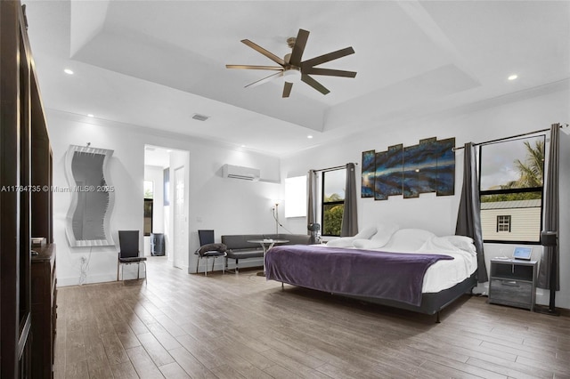 bedroom with visible vents, a wall mounted air conditioner, recessed lighting, wood finished floors, and a raised ceiling