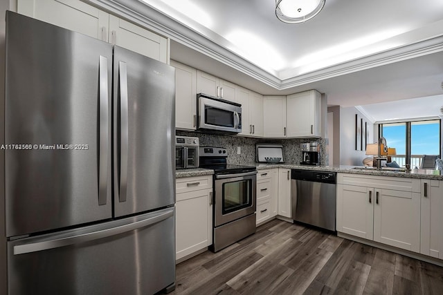 kitchen featuring ornamental molding, appliances with stainless steel finishes, dark wood-style floors, white cabinets, and a sink