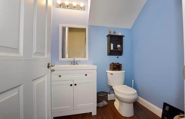 1020 NW Leonardo Cir, Port St Lucie, FL 34986 - bathroom with vanity, wood finished floors, baseboards, vaulted ceiling, and toilet