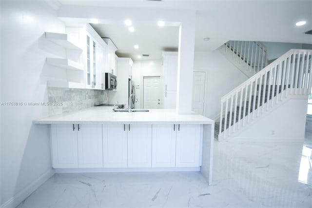 kitchen featuring glass insert cabinets, black microwave, a peninsula, white cabinets, and marble finish floor