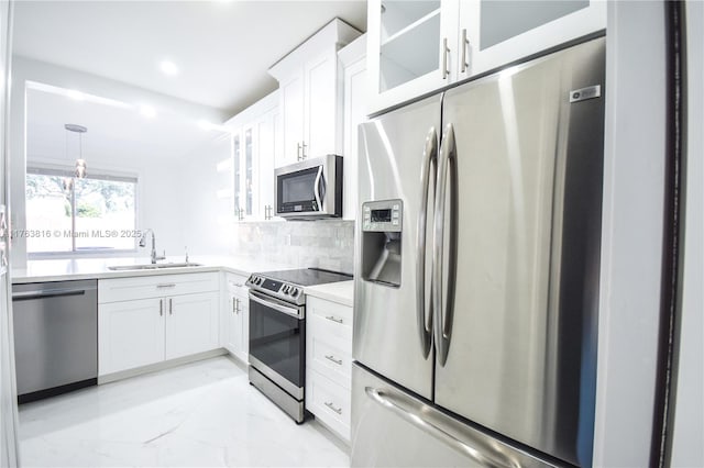 kitchen with tasteful backsplash, appliances with stainless steel finishes, white cabinets, marble finish floor, and a sink