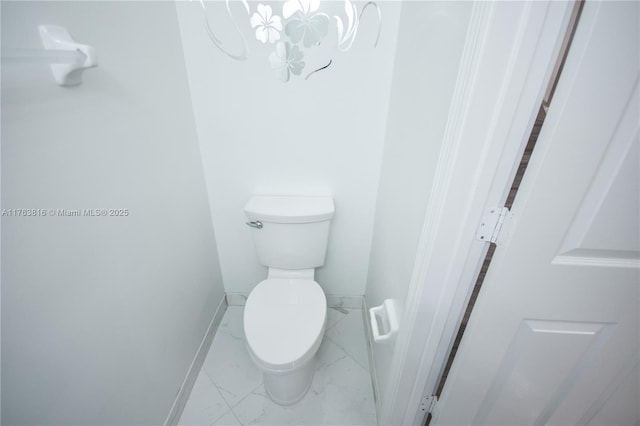 bathroom with baseboards, toilet, marble finish floor, and a chandelier