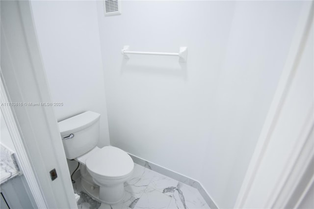 bathroom with toilet, visible vents, marble finish floor, and baseboards