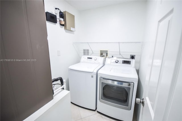 washroom featuring independent washer and dryer, light tile patterned flooring, and laundry area