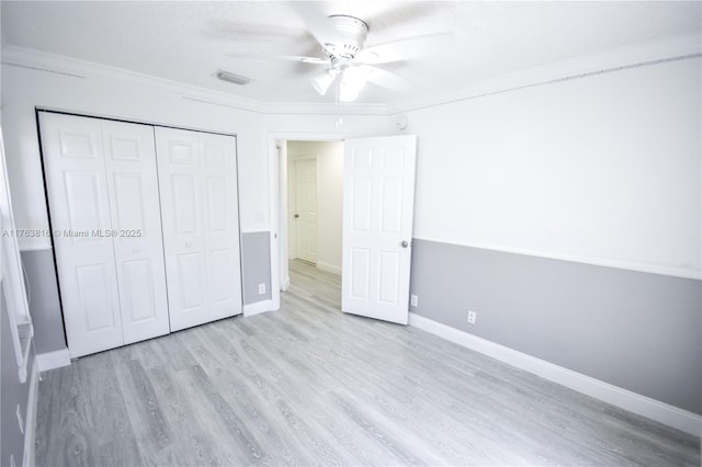 unfurnished bedroom featuring visible vents, baseboards, a closet, and wood finished floors