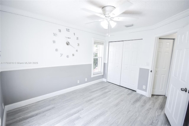 unfurnished bedroom featuring wood finished floors, baseboards, ceiling fan, ornamental molding, and a closet