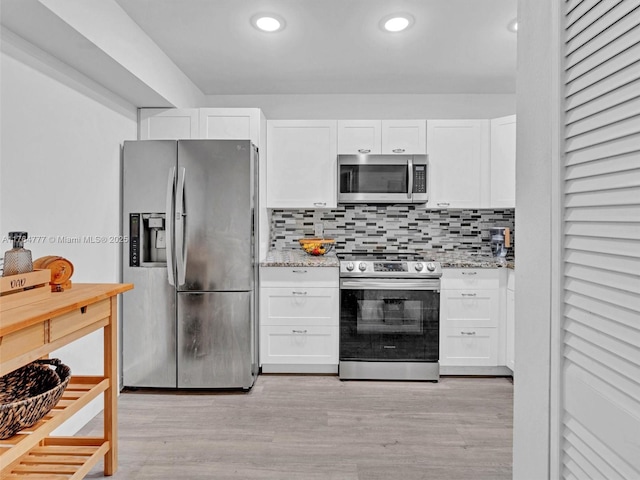 900 NE 195th St Unit 504, Miami, FL 33179 - kitchen featuring stainless steel appliances, tasteful backsplash, light wood-style floors, and white cabinets