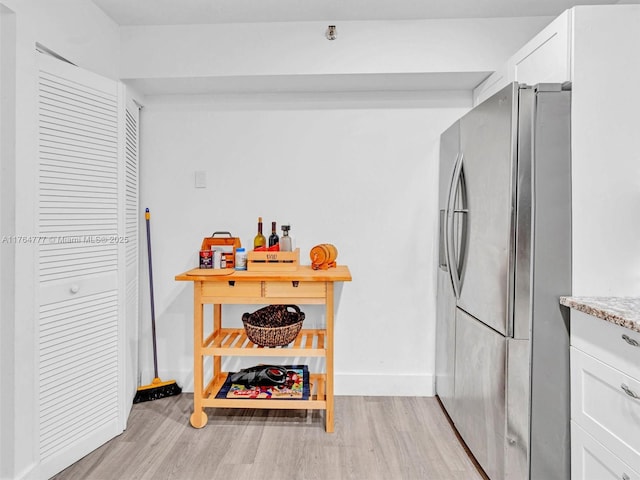 900 NE 195th St Unit 504, Miami, FL 33179 - kitchen with baseboards, light stone countertops, light wood-type flooring, freestanding refrigerator, and white cabinetry