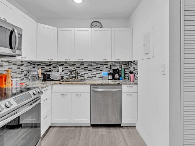900 NE 195th St Unit 504, Miami, FL 33179 - kitchen with light wood-style flooring, a sink, white cabinets, appliances with stainless steel finishes, and tasteful backsplash