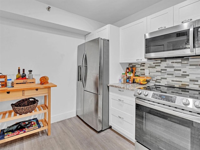 900 NE 195th St Unit 504, Miami, FL 33179 - kitchen with light stone counters, decorative backsplash, light wood-style flooring, stainless steel appliances, and white cabinetry