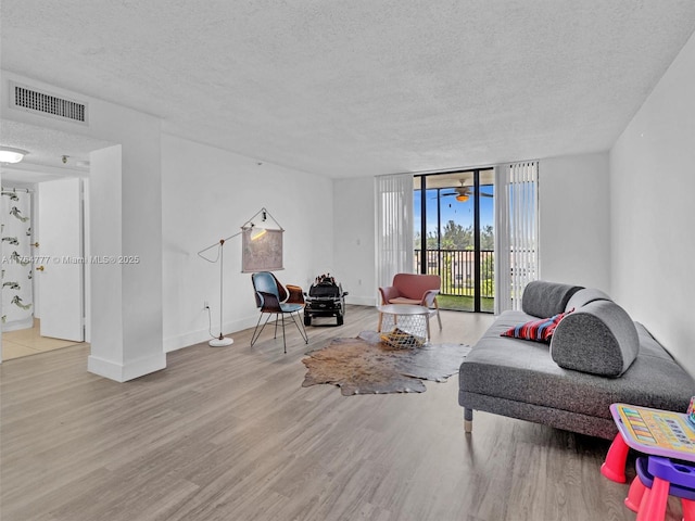 900 NE 195th St Unit 504, Miami, FL 33179 - living room with visible vents, baseboards, expansive windows, wood finished floors, and a textured ceiling